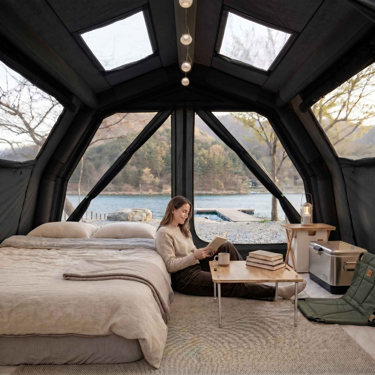 Cozy atmosphere inside the Coody all-season inflatable tent made of technical cotton: panoramic TPU glazing, double bed, wooden furniture and transparent skylights