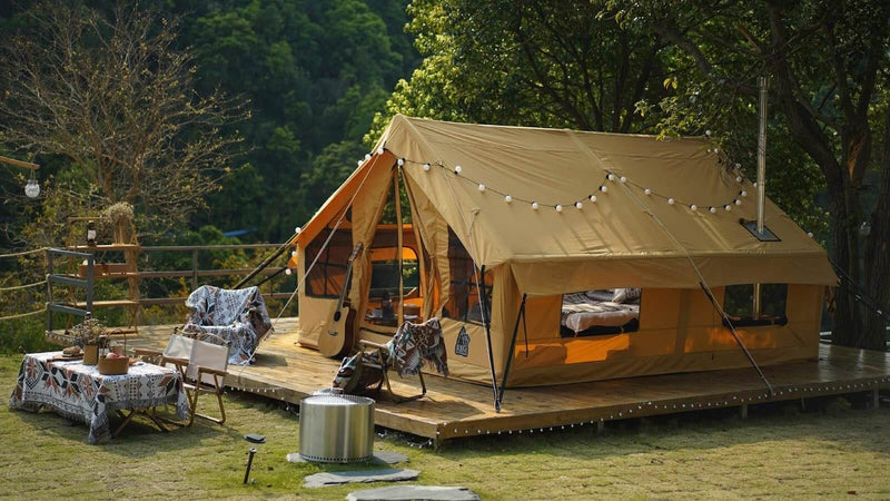 Panda Large glamping tent is laid out on a wooden platform, with tables, chairs and personal belongings of vacationers in front of it